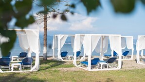 A beach with white canopies and blue chairs. - Saint Peter Bay – 1st Floor Holiday Home with Shared Pool, Wi-Fi & Air Conditioning (Lefkimmi)