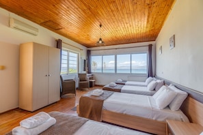 A hotel room with wooden ceilings, large windows, two beds, a desk, and a chair.