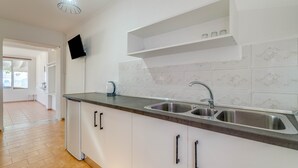Eine moderne Küche mit doppelter Spüle, weißen Schränken, integriertem Fernseher und einer Deckenleuchte.