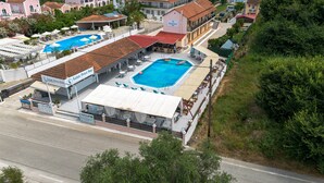 Ein Küstenhotel mit mehreren Schwimmbecken, einem Strandbereich und Blick auf das Meer.