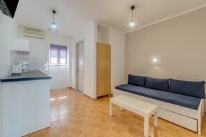 Un salon moderne comprenant un canapé, une table basse et un coin cuisine avec un comptoir et un évier.