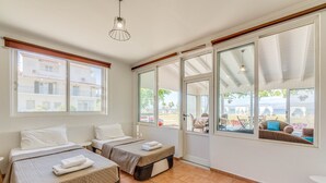 Ein Hotelzimmer mit zwei Betten, einem großen Fenster mit Blick nach draußen und einer Deckenleuchte.
