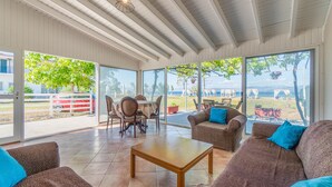 Ein überdachter Patio-Bereich mit Esstisch, Stühlen und Sofas.
