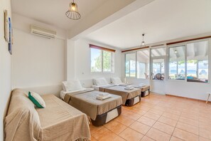 Une chambre d’hôtel avec trois lits, une fenêtre donnant sur un beau paysage et un appareil de climatisation.
