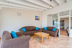 Un salon avec deux canapés, une table basse et une porte donnant sur la cuisine.
