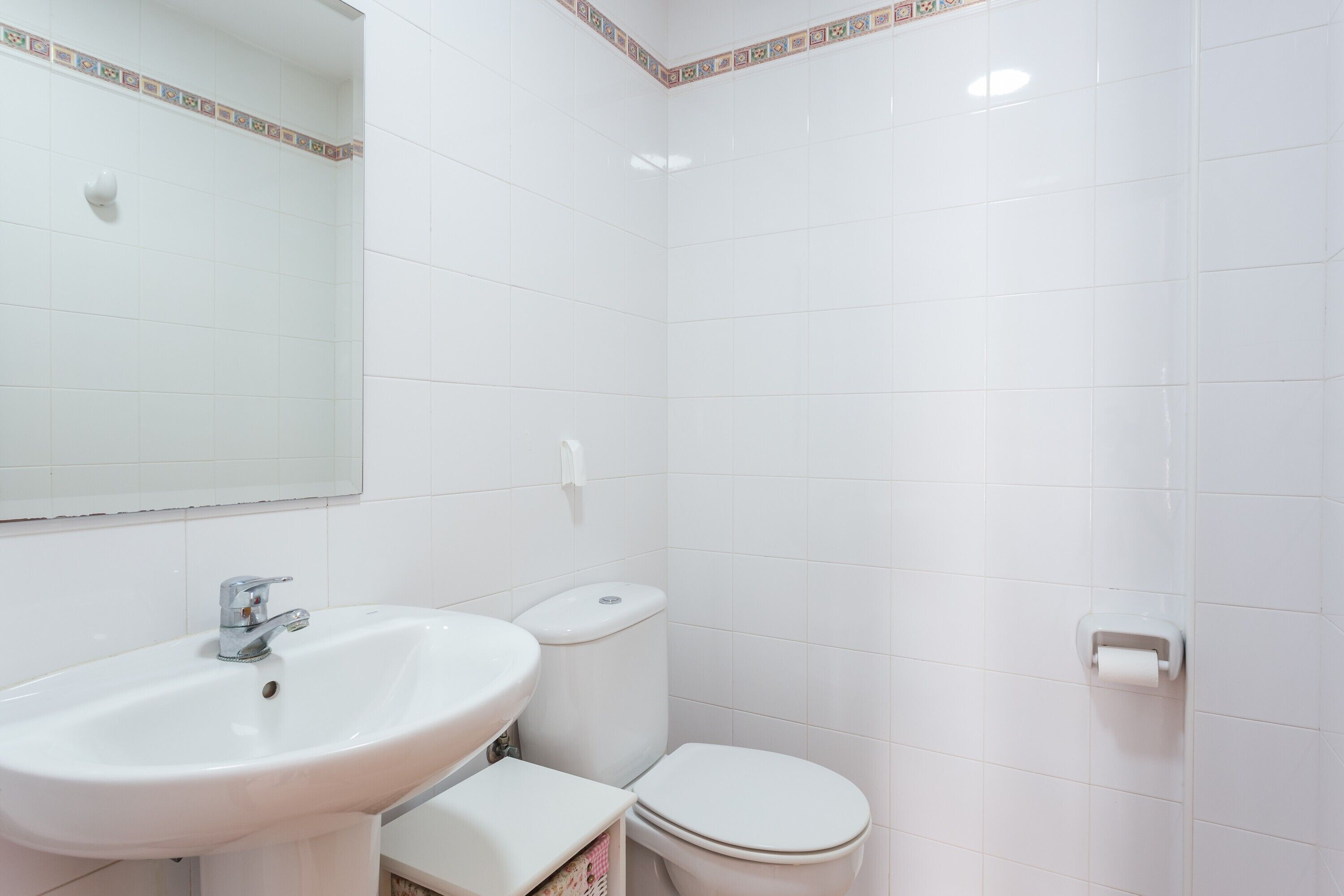 Un baño con lavamanos, inodoro y espejo.