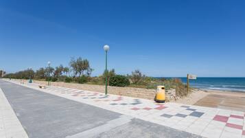 A coastal walkway with a checkered pattern, a lamp post, and a trash bin.