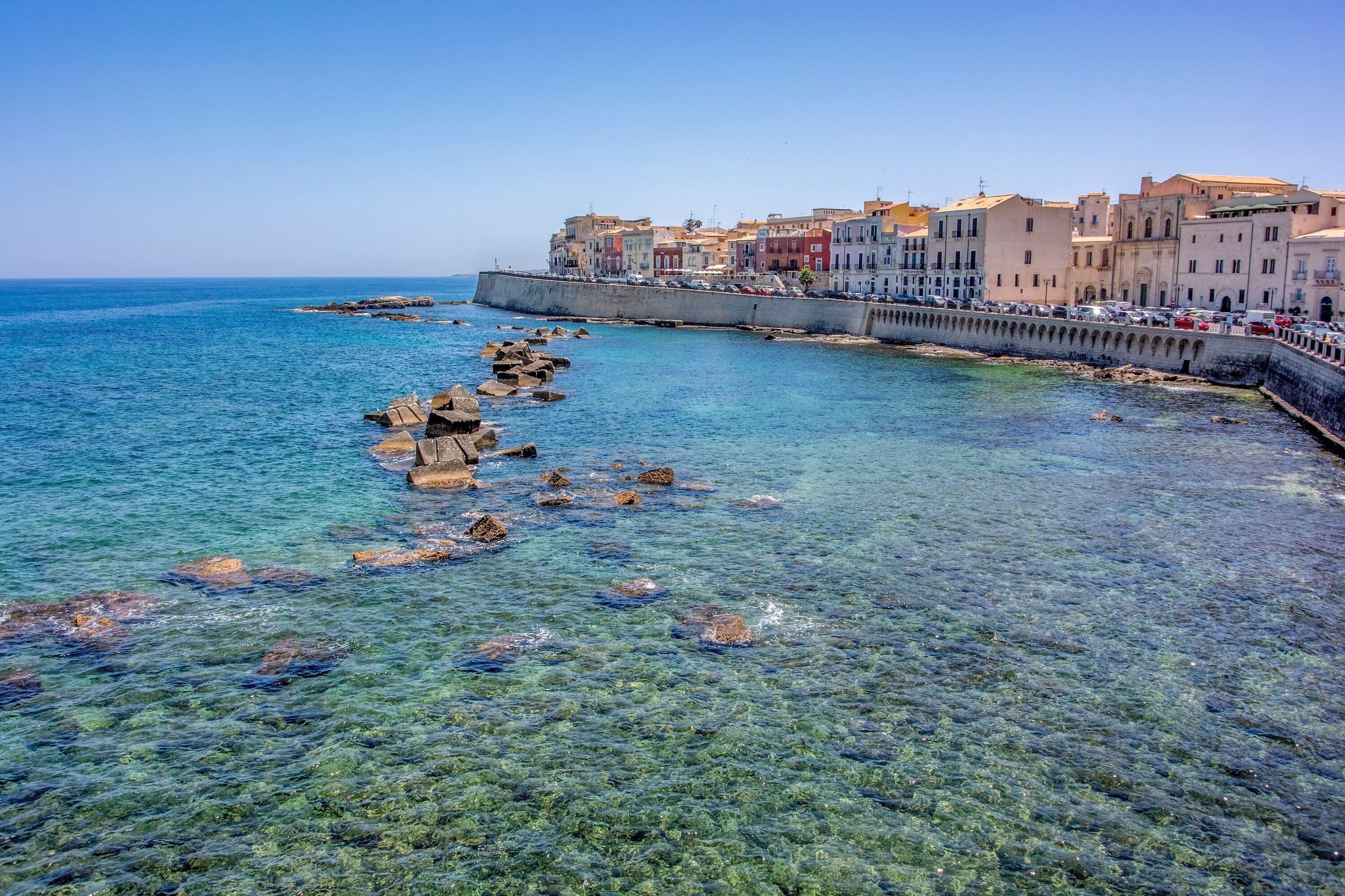 Une ville côtière aux eaux cristallines, aux formations rocheuses et aux bâtiments aux couleurs vives qui bordent le front de mer.