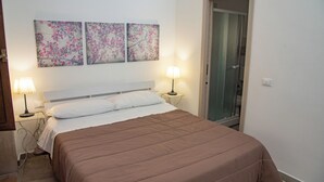 Un dormitorio con una cama, dos lámparas de noche y tres cuadros florales colgados en la pared.