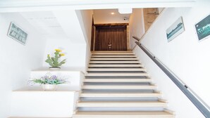 Una escalera con barandilla de madera y una pared blanca decorada con cuadros.