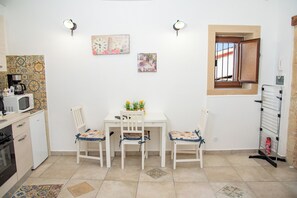 A kitchen with a white table, two chairs, a microwave, and a coffee maker.