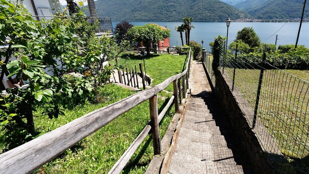 Un sentiero conduce a un edificio con vista su un lago e montagne.