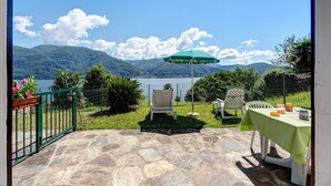 Un patio con pavimento in pietra, un tavolo con tovaglia verde, una sedia e un ombrellone.