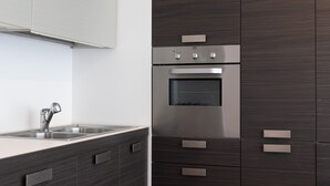 Una cocina moderna con horno de acero inoxidable, lavamanos empotrado y muebles de madera oscura.