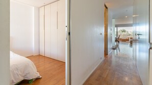 Habitación de hotel moderna con piso de madera, cama, armario y vista al área de estar exterior.