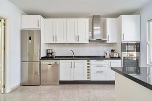 A modern kitchen with white cabinets, stainless steel appliances, and a black countertop.