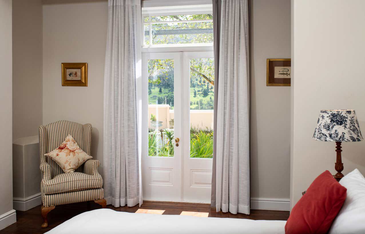 Un dormitorio con una cama, una silla, una lámpara y una puerta que da a un jardín.