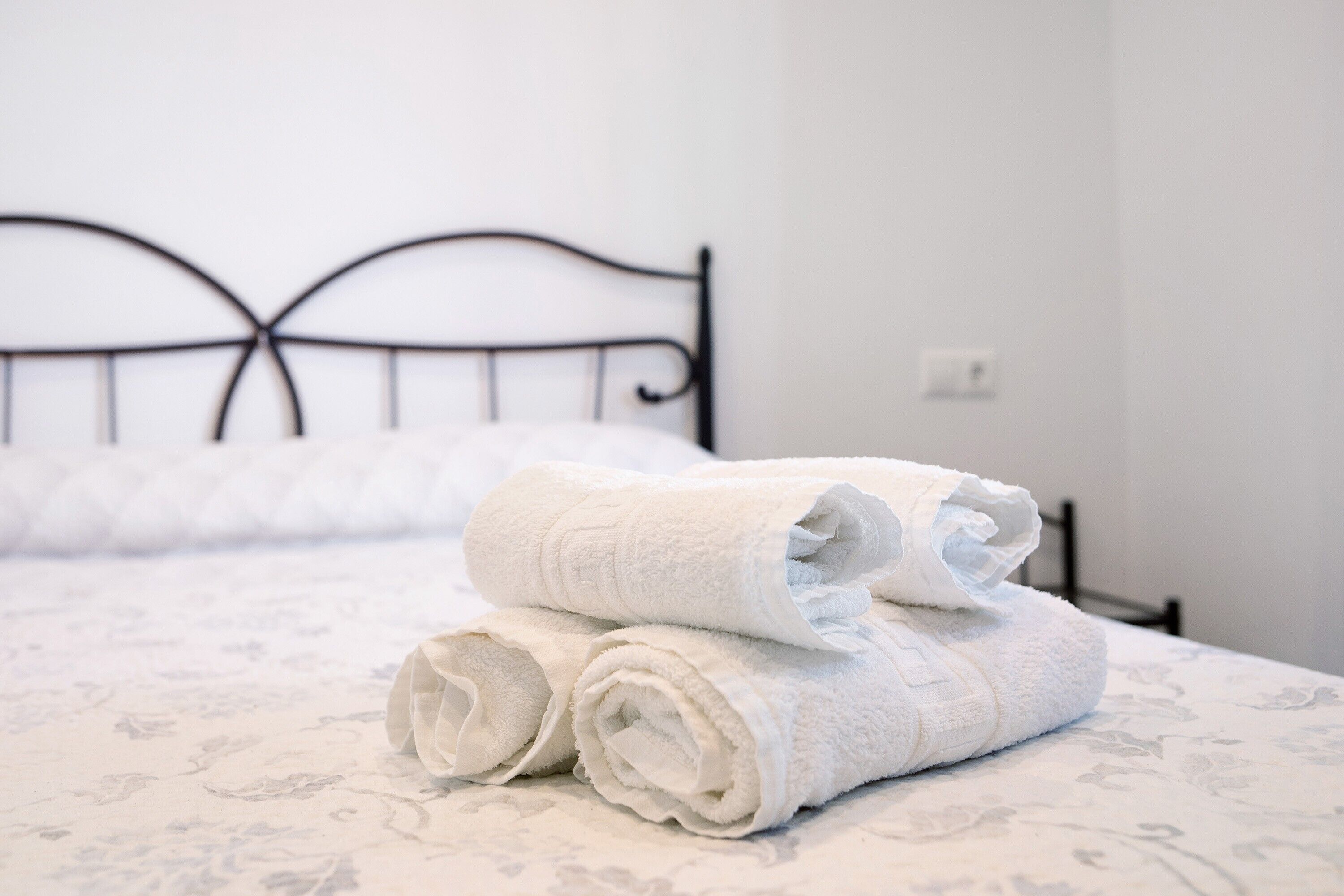 Una cama bien hecha con sábanas blancas y cabecero de metal.
