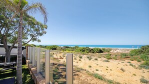 A coastal property with a sandy landscape, a bench, and a view of the sea. - Holiday Home "Novobarrosa A" with Sea View, Shared Pool & Wi-Fi (Chiclana de la Frontera)