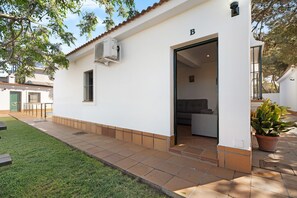 Un bâtiment blanc avec une terrasse carrelée, une porte et un pot de fleurs.