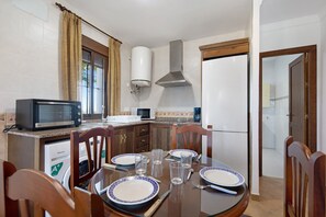 A kitchen with a dining table set for two, a microwave, a toaster, and a washing machine.