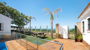 A pool, patio, and view of the sea.