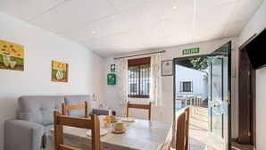 A dining area with a table, chairs, a sofa, and a sign reading 'SALIDA' indicating an exit.