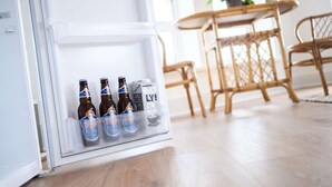 A refrigerator with four bottles of Tiger beer and a carton of oat milk.