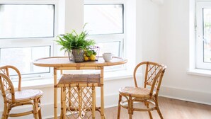 A room with a round wooden table, two wicker chairs, a potted plant, and a ceiling light fixture.