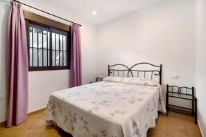 Ein Schlafzimmer mit Bett, Vorhängen, Fenster und Nachttisch.