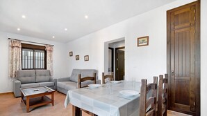 Un comedor con una mesa preparada para cuatro, un sofá y una puerta de madera.