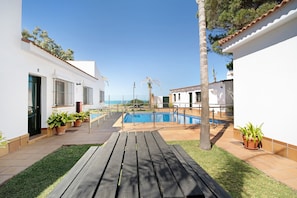 Un espace piscine doté d’une terrasse en bois, de plantes en pot et offrant une vue sur la mer.