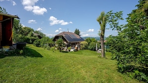 Een huis met een schuin dak, een tuin met gazon en een boom.