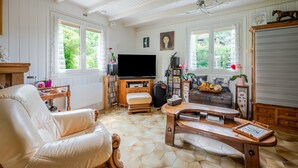 Een woonkamer met een televisie, houten meubels en een boekenkast.