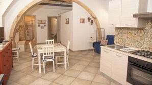 Una cocina con comedor, que presenta un arco, salpicadero de azulejos y electrodomésticos modernos.