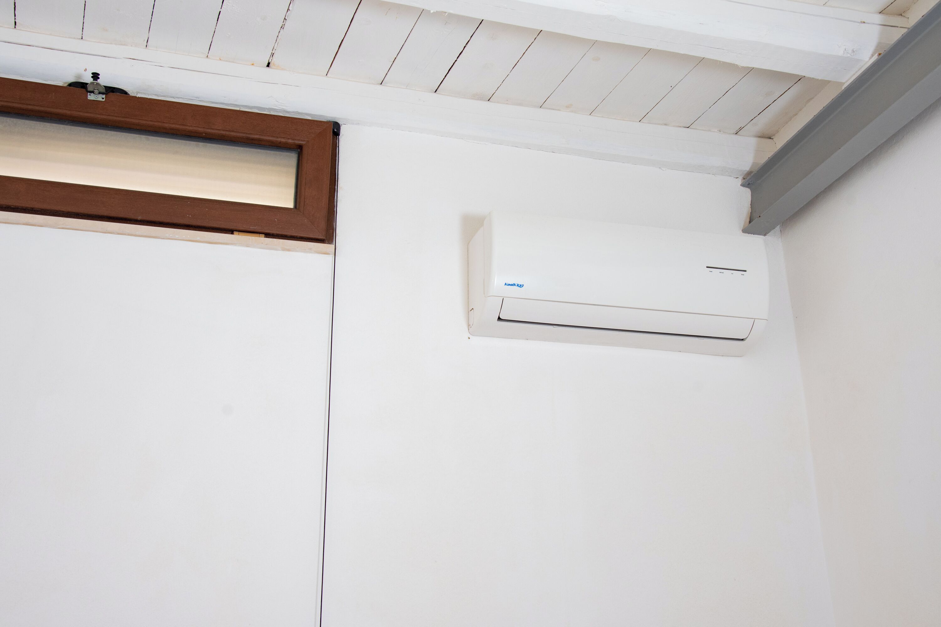 Eine weiße Wand mit Fenster und Klimaanlage.