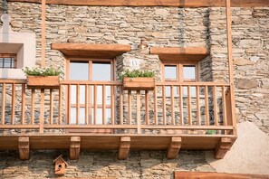 Un bĂątiment en pierre dotĂ© de balcons en bois, de fenĂȘtres numĂ©rotĂ©es et dâune nichoir.