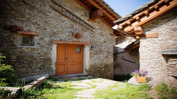 A stone building with a wooden door, a small window, and a stone pathway leading to a flower bed. - Chalet 'Civico 2' with Mountain View, Balcony and Wi-Fi (Marmora)