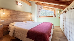 A wooden-paneled bedroom with a bed, nightstands, and a window with curtains. - Chalet 'Civico 2' with Mountain View, Balcony and Wi-Fi (Marmora)