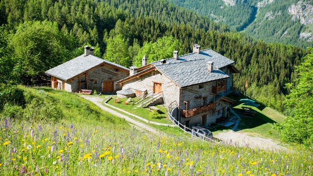 A mountain lodge with stone walls, wooden balconies, and a clear view of the surrounding forest and mountains. - Chalet 'Civico 5' with Mountain View, Shared Garden and Wi-Fi (Marmora)