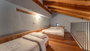 A bedroom with two beds, wooden beams, a small window, and a staircase. - Chalet 'Civico 5' with Mountain View, Shared Garden and Wi-Fi (Marmora)