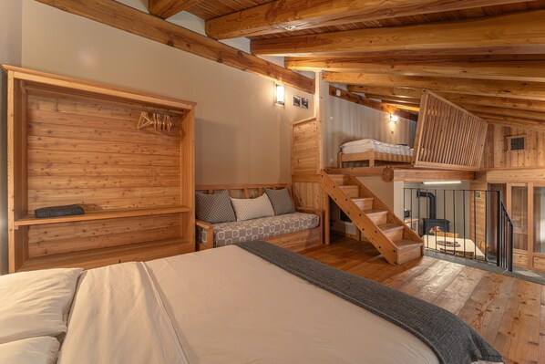 Ein Holzinnenraum mit einem Bett, einer Couch, einer Treppe und einem Kamin.