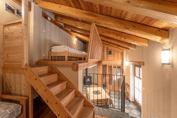 A wooden staircase leading to a loft bedroom with a bed and a fireplace.