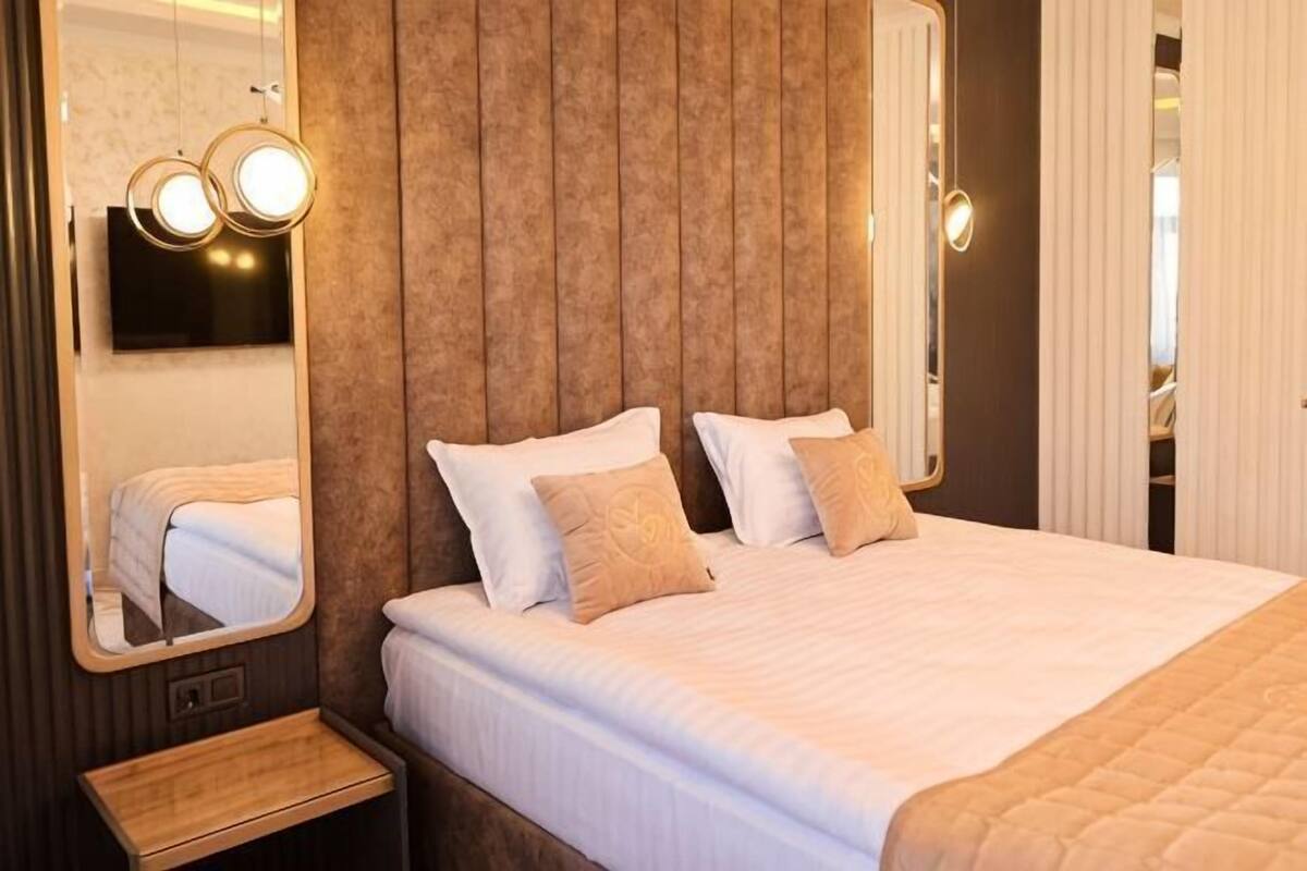 A bedroom with a large bed, a wooden headboard, a mirror, and bedside lamps.