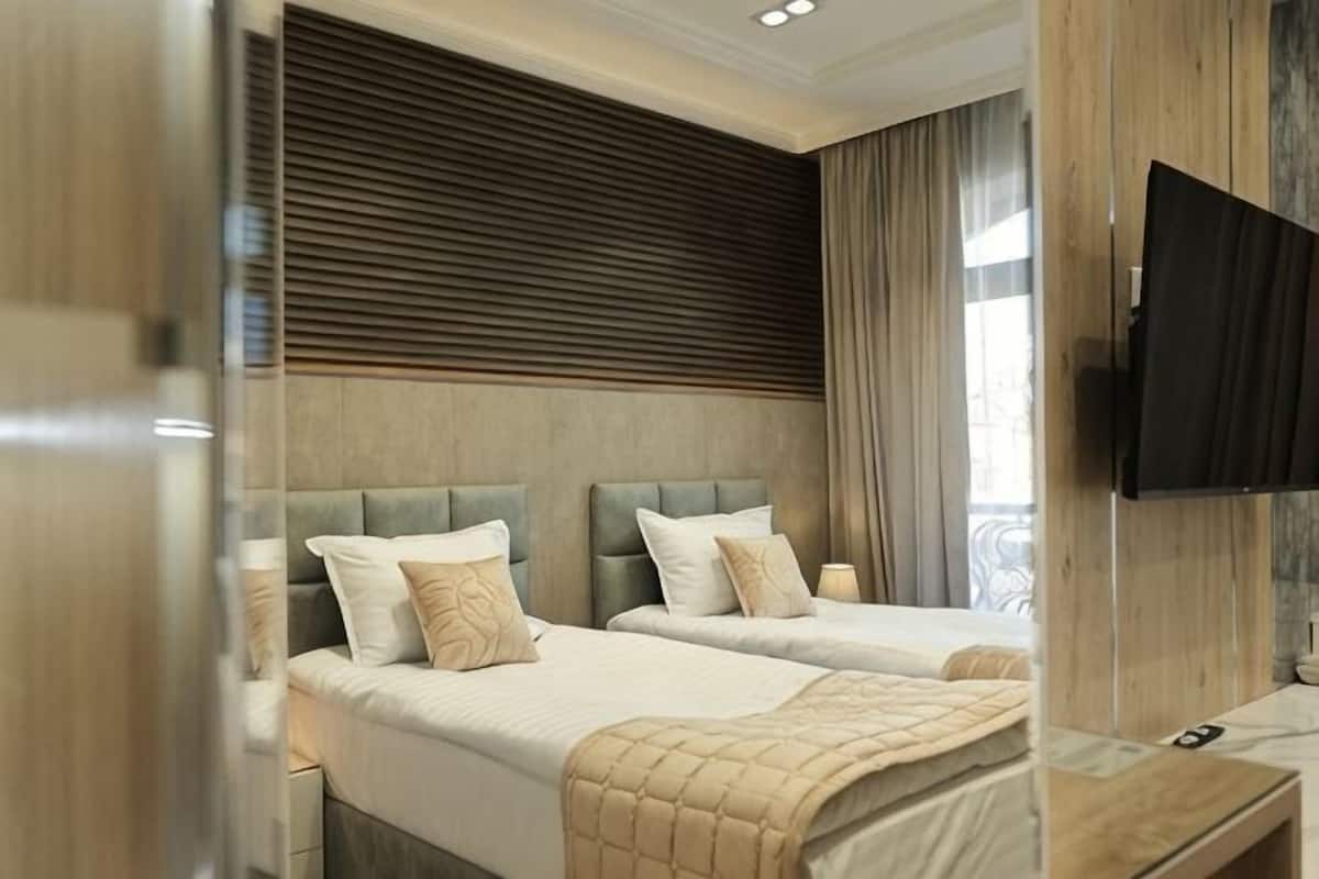 A hotel room with two beds, a TV, and a wooden headboard.