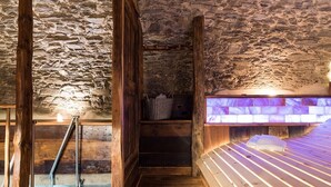 A stone-walled room with a wooden bench, a small staircase, and a bench with a purple-lit backrest. - Chalet 'Civico 11' with Mountain View, Balcony and Wi-Fi (Marmora)