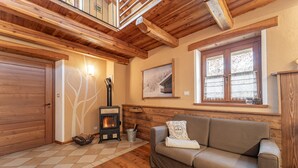 Una habitación acogedora con chimenea, suelo de madera, un sofá y una ventana con cortinas.