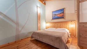 A room with a bed, wooden flooring, a wall with a tree silhouette, and a framed picture on the wall. - Chalet 'Civico 7' with Mountain View, Shared Terrace and Wi-Fi (Marmora)