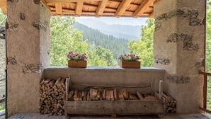 A rustic wooden structure with a stone bench and flower pots, overlooking a mountainous landscape. - Chalet 'Civico 7' with Mountain View, Shared Terrace and Wi-Fi (Marmora)