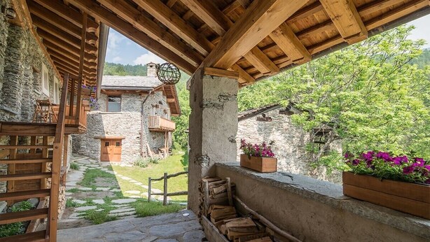 A rustic stone building with a wooden pergola, stone steps, and a garden view. - Chalet 'Civico 7' with Mountain View, Shared Terrace and Wi-Fi (Marmora)